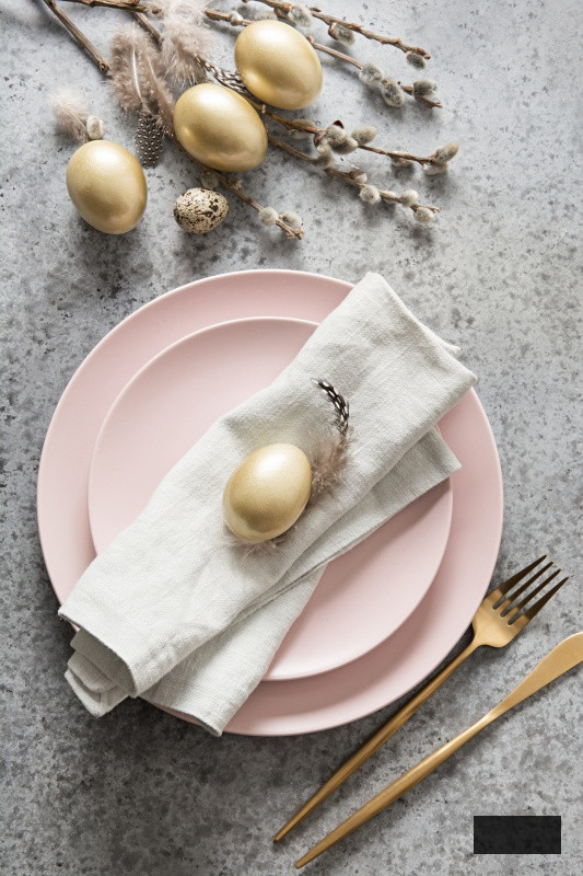Easter table setting with pink plate and golden eggs on grey stone table