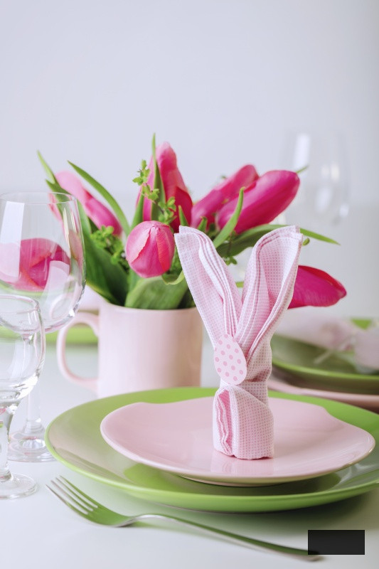 Happy easter. Decor and table setting of the Easter table is a vase with pink tulips and dishes of pink and green color.