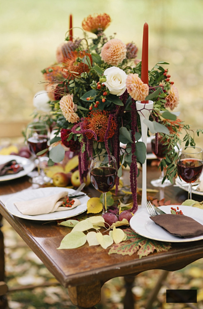 Outdoor fall dining with rich floral centerpiece and candles
