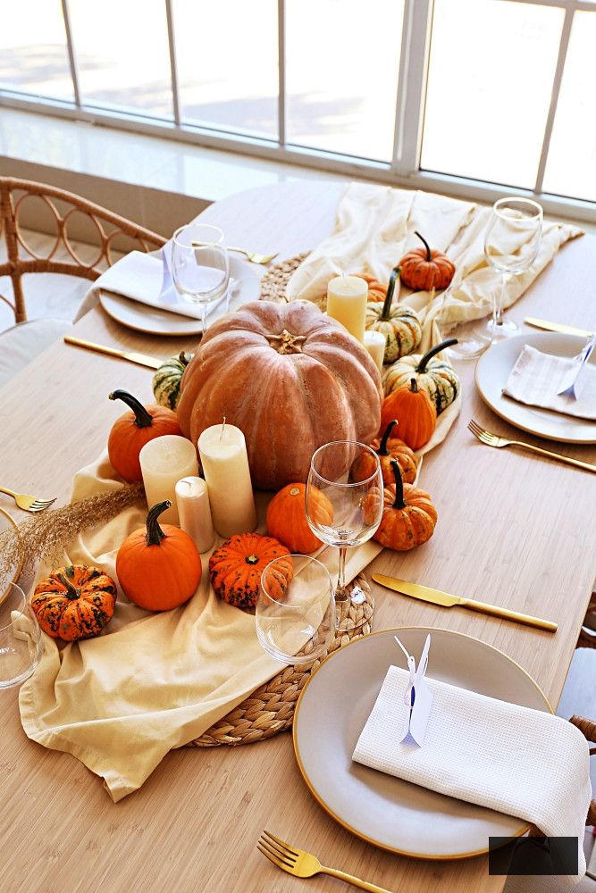 Beautiful autumn table setting with pumpkins and candles in room