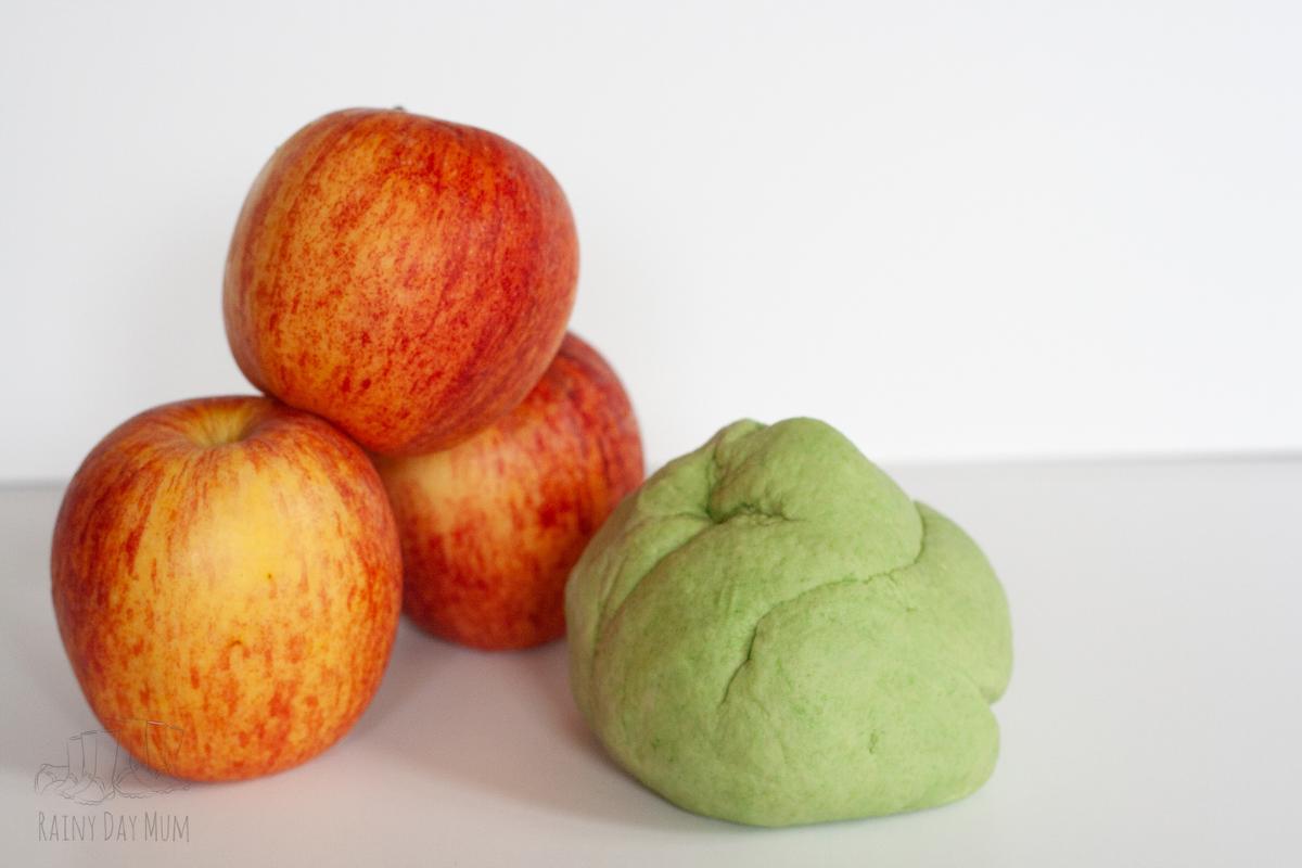 apple pie play dough accompanied by some real apples on a white backdrop.