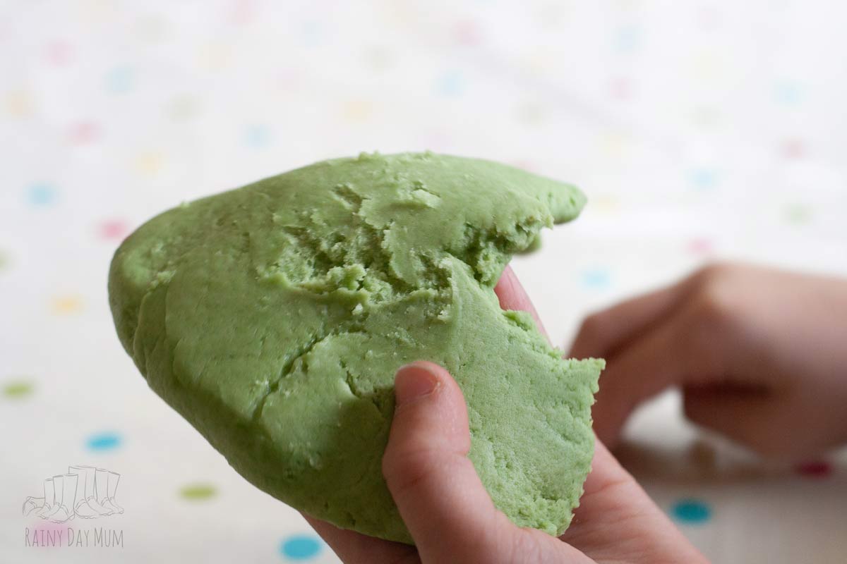 child engaging with apple-scented playdough at the table, pulling it apart and rolling it with their fingers.