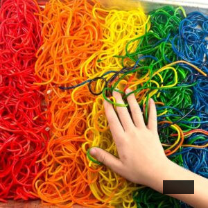 a child playing with rainbow coloured noodles
