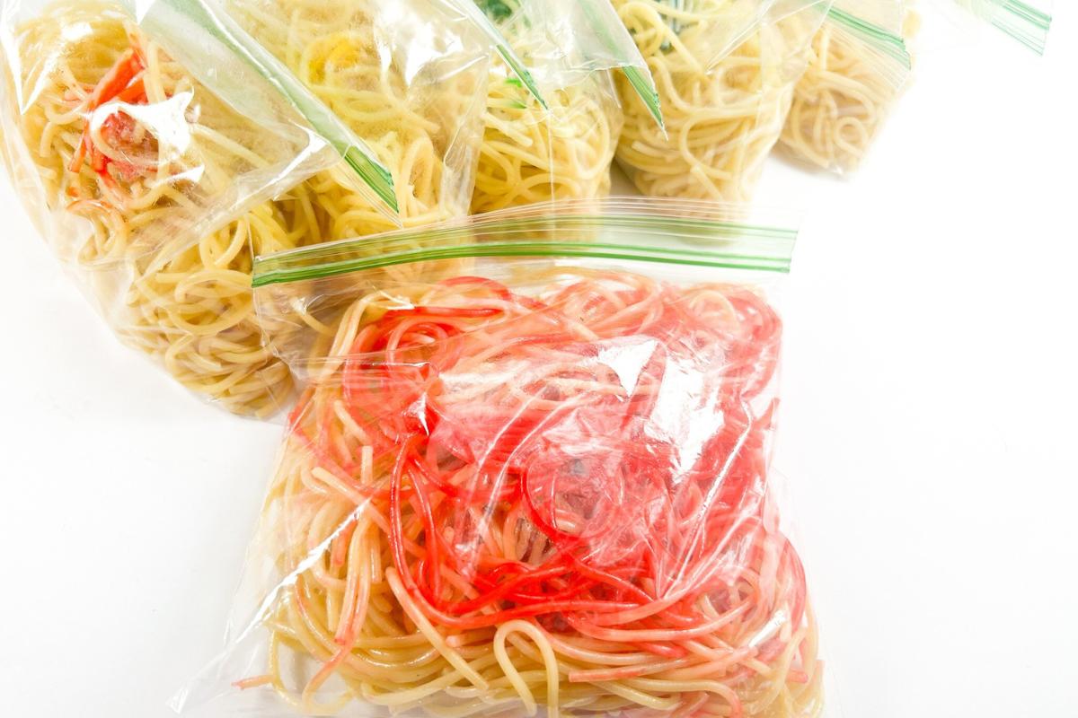 preparing red tinted spaghetti for sensory activities in a sandwich bag