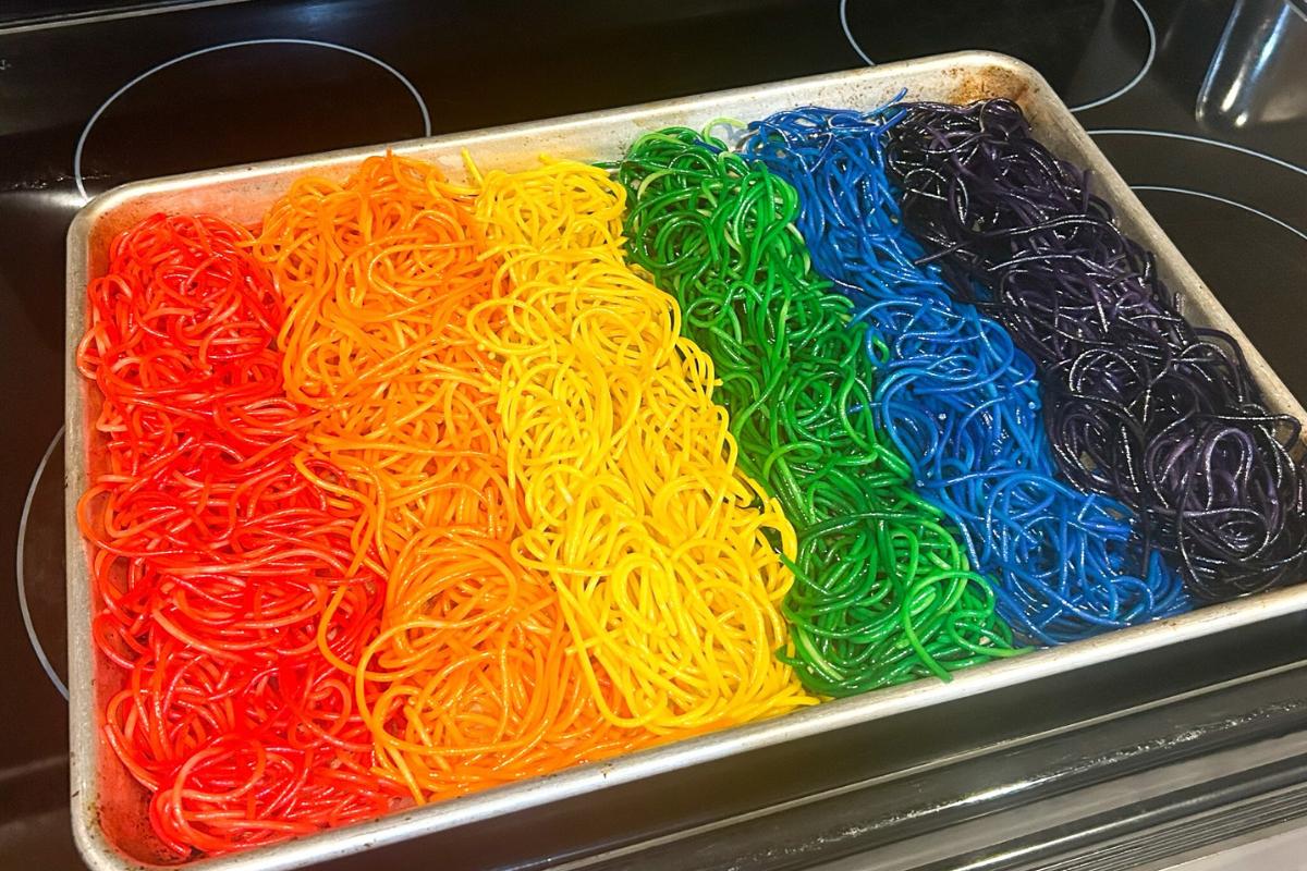 a sensory tray featuring stripes of rainbow spaghetti