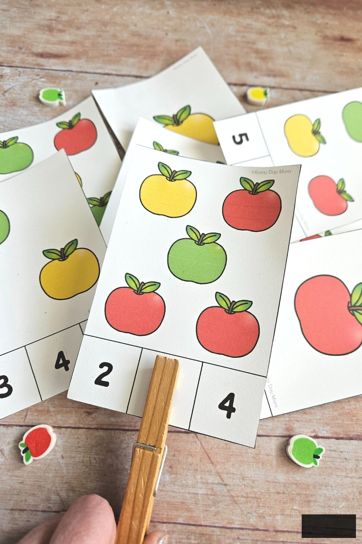 Clipping numbers on apple counting cards for autumn learning with preschoolers.