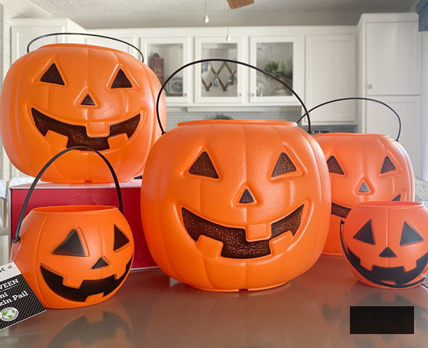 Craft chic Halloween decorations with a DIY Pottery Barn Jack-O-Lantern replica. Achieve the upscale appearance for under $5 using plastic buckets, paint, and LED candles.