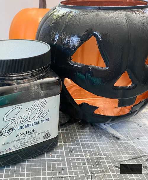 Craft chic Halloween decorations with a DIY Pottery Barn Jack-O-Lantern replica. Achieve the upscale appearance for under $5 using plastic buckets, paint, and LED candles.