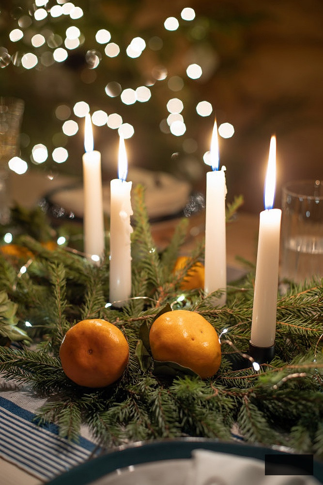 Christmas centerpiece with evergreens, candles, and oranges