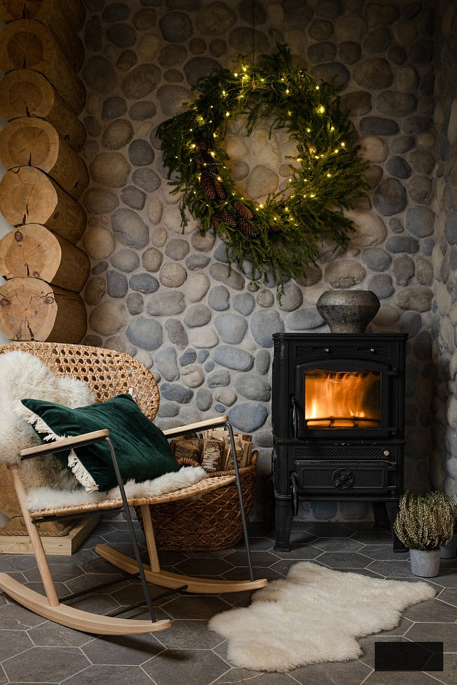 Free standing fireplace against a stone wall in a Christmas cabin
