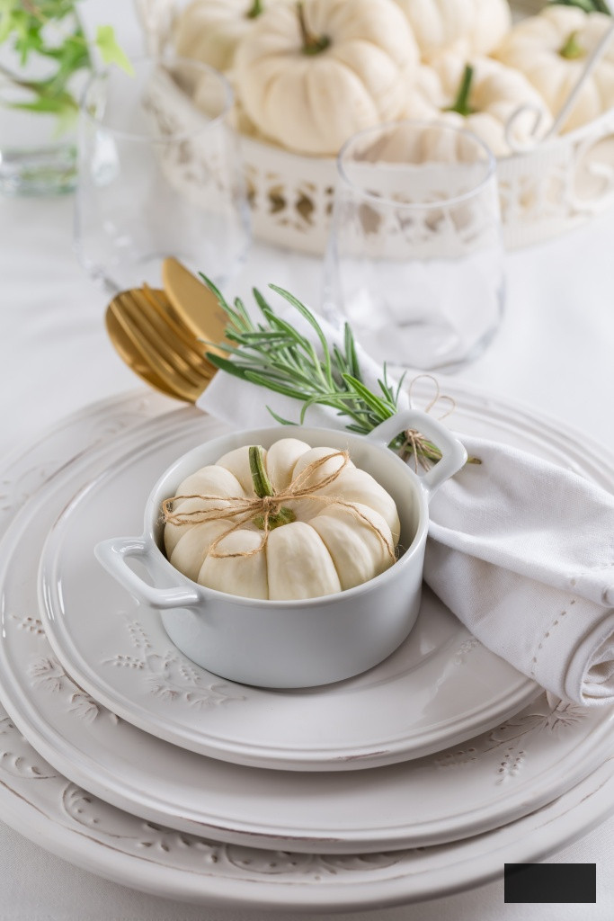 Place setting for Thanksgiving with small white pumpkin and rosemary in white color