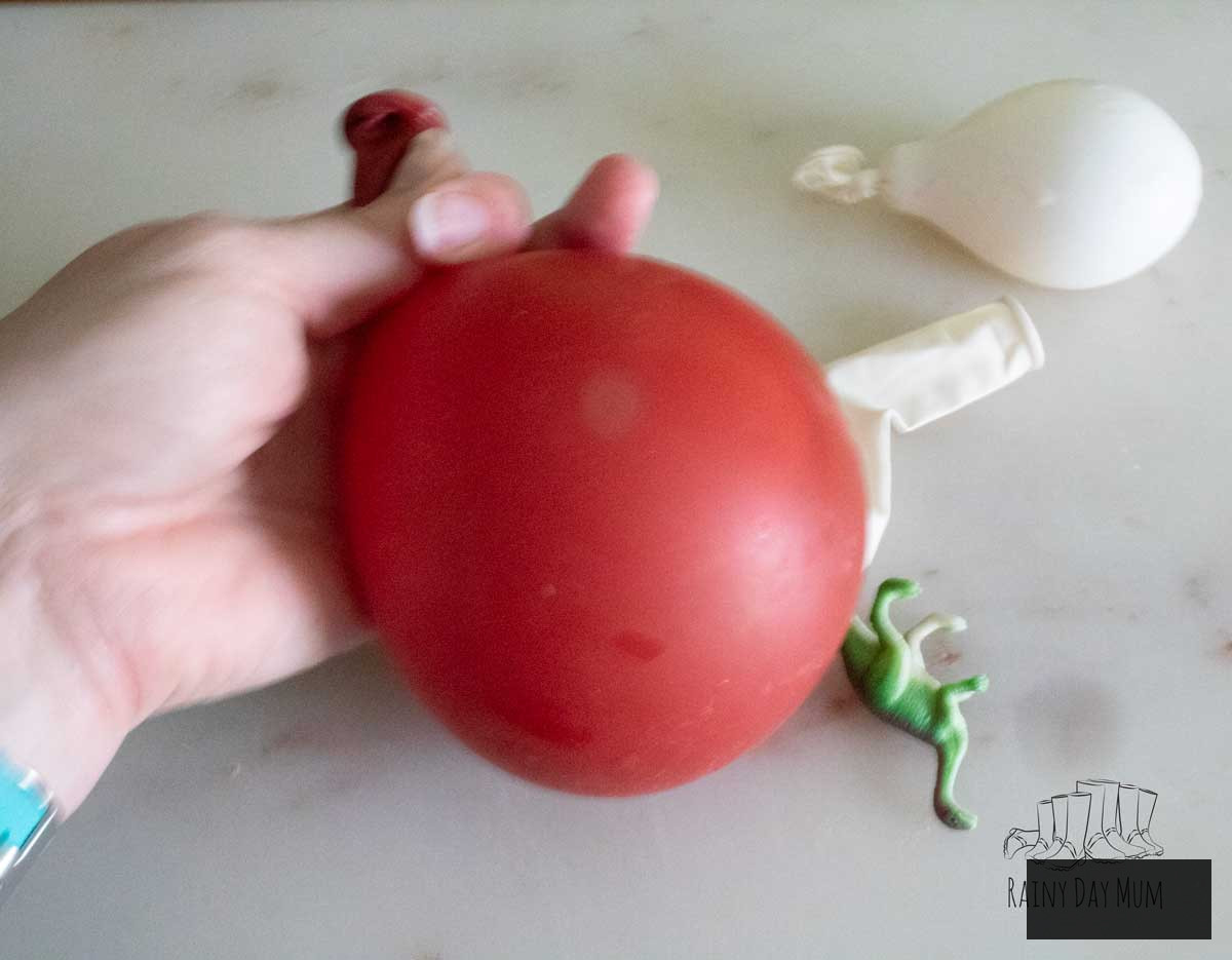Water balloon filled with a toy dinosaur and water, prepared for freezing.