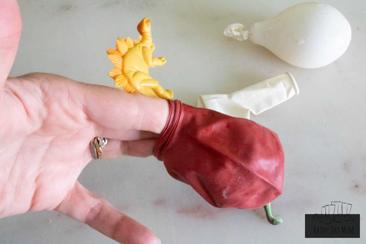 Inserting a small toy dinosaur inside the balloon to create a frozen dinosaur egg.