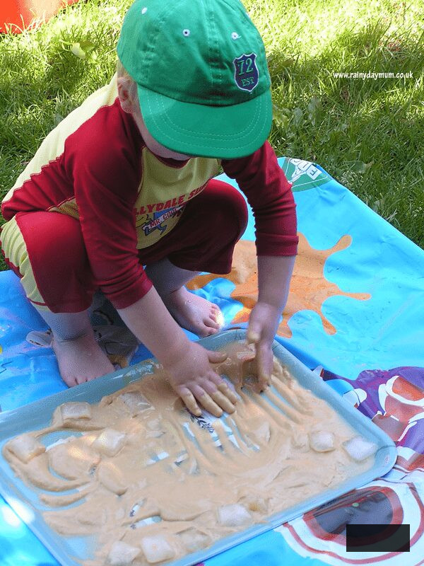 child playing with ice and pudding mix in the garden