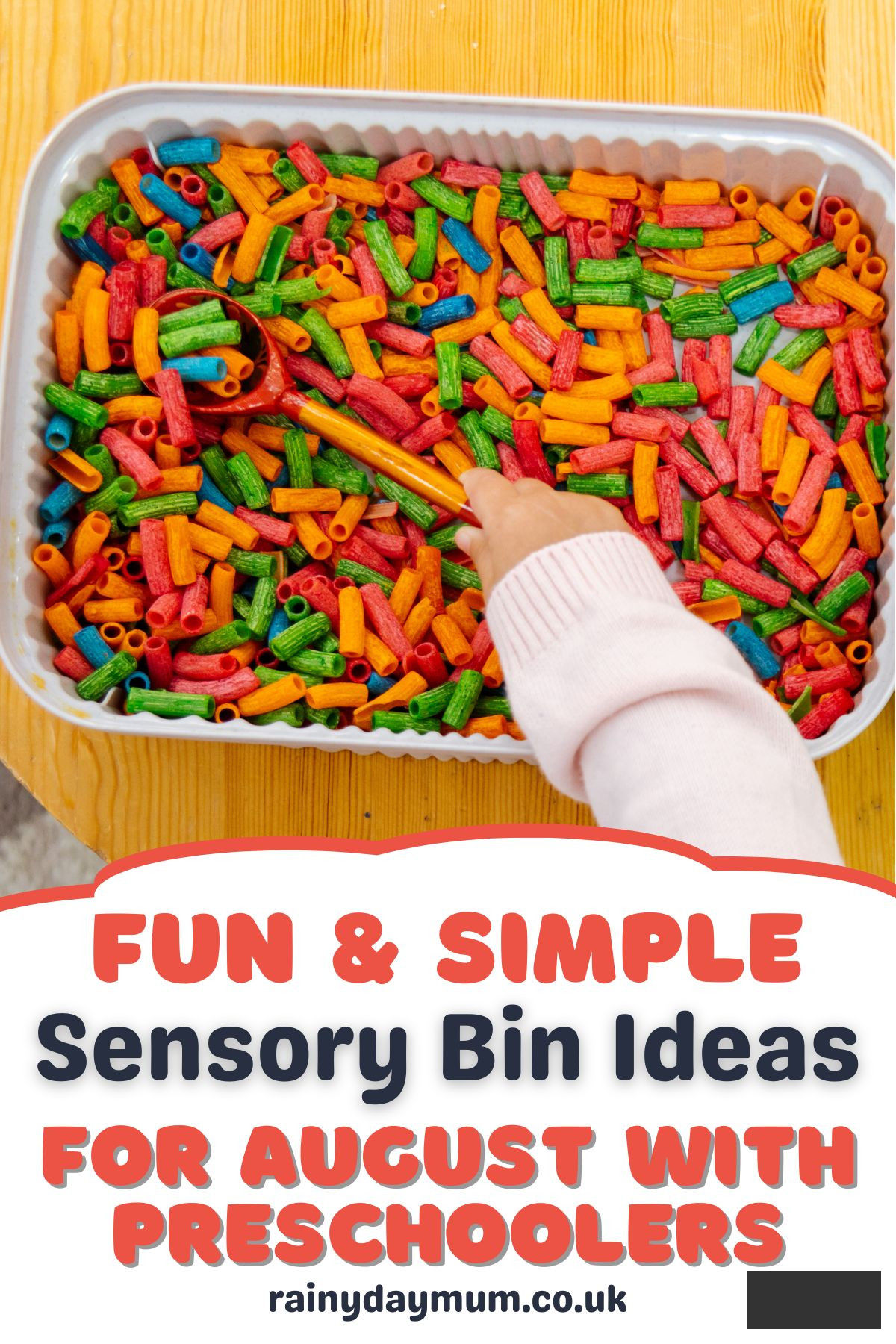 Child’s hand scooping colorful dyed pasta from a sensory bin with a red spoon, text overlay reads 'Fun & Simple Sensory Bin Ideas for August with Preschoolers.' 