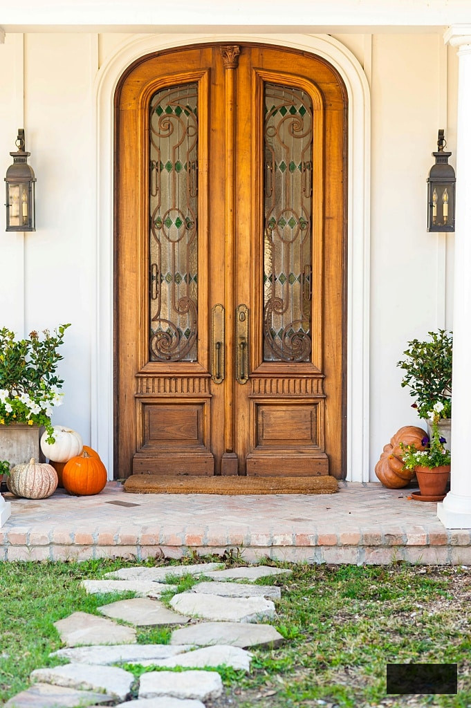 arched wooden double front door on white house