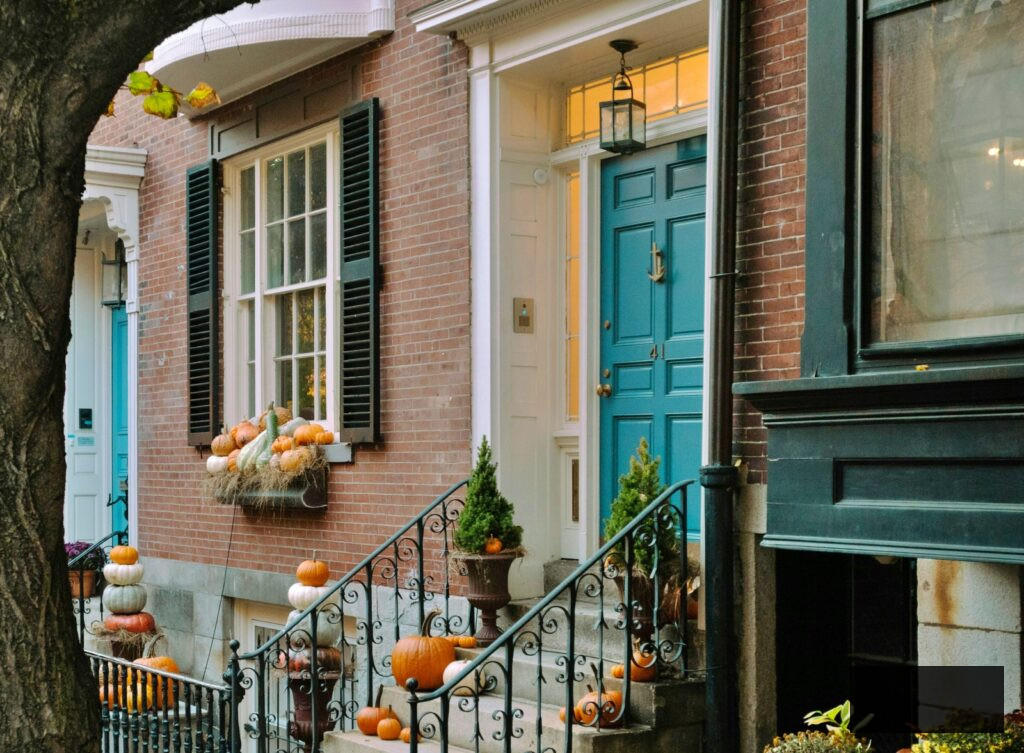 loads of pumpkins decorating the front of a brick row house