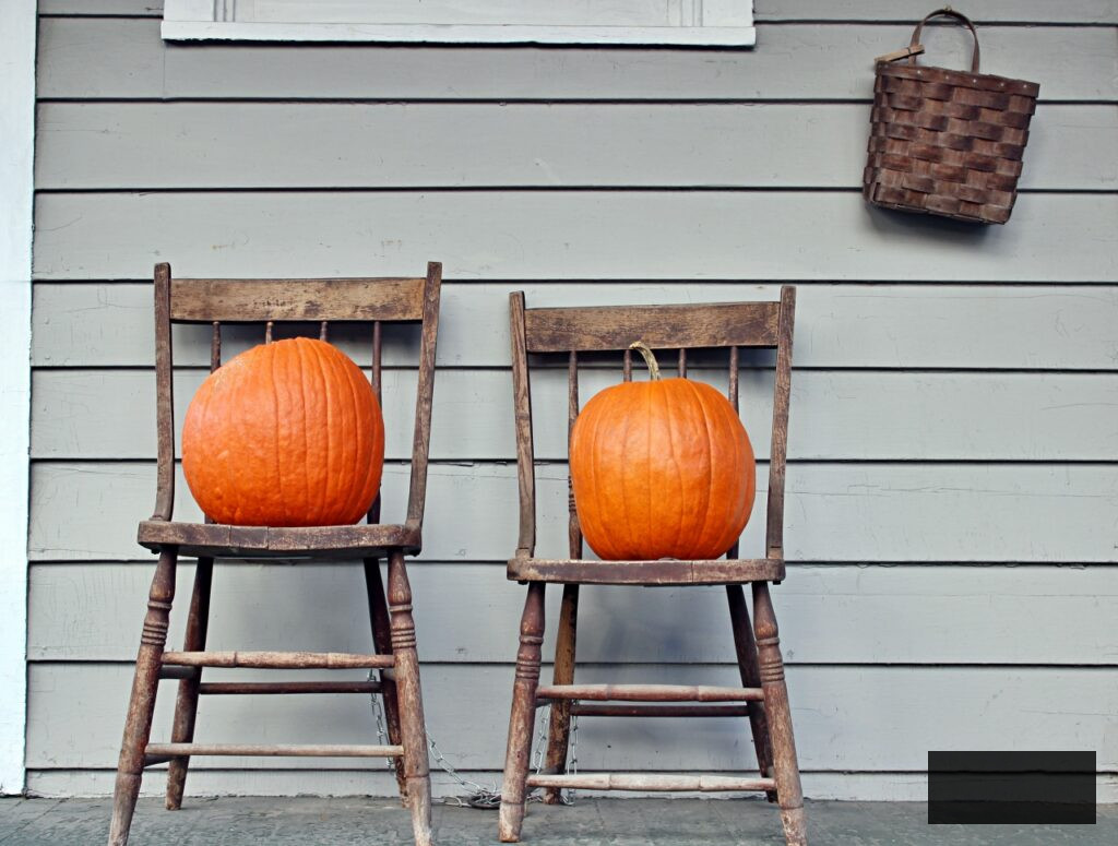 Vintage Chairs with Large Orange Pumpkins on a Fall Porch