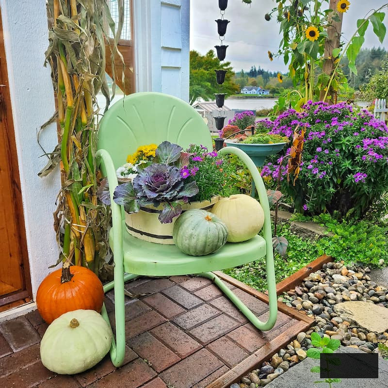 autumn porch decorating ideas: green vintage chair with fall flowers and pumpkins on it