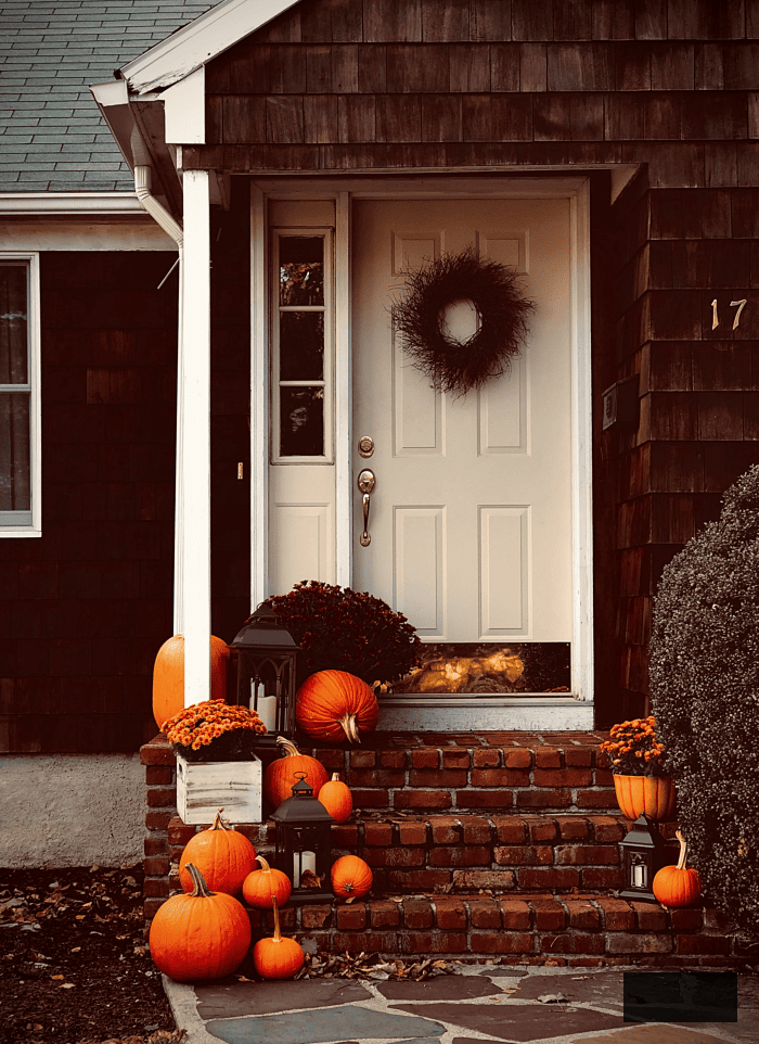dark brown house with pumpkins on porch
