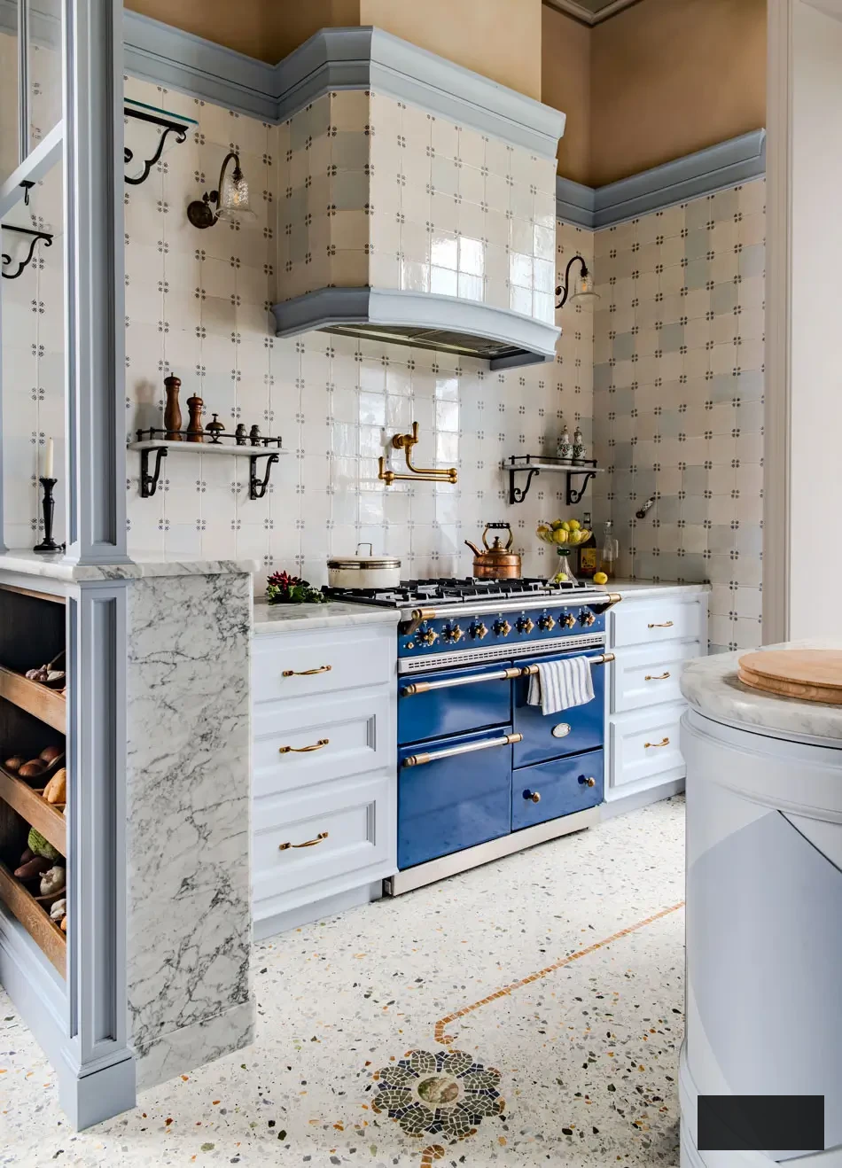 Detailed view of an exquisite La Cornue blue enamel range with brass hardware, surrounded by marble counters and pale blue cabinetry in a villa kitchen on Lake Maggiore. Handmade tiled walls and wrought-iron shelves complete this sophisticated fusion of British craftsmanship and Italian artistry.