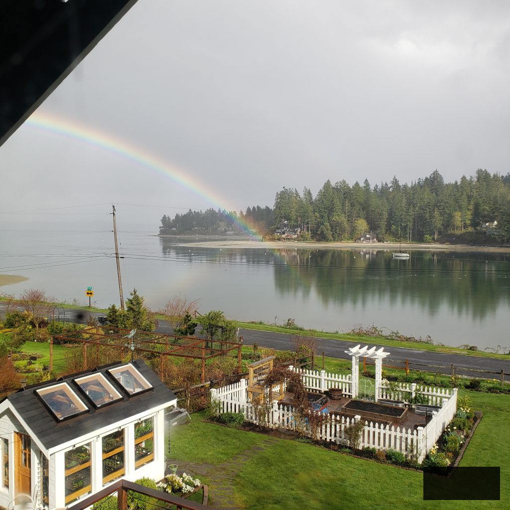 image of the white picket fence cut flower garden and greenhouse featuring a rainbow