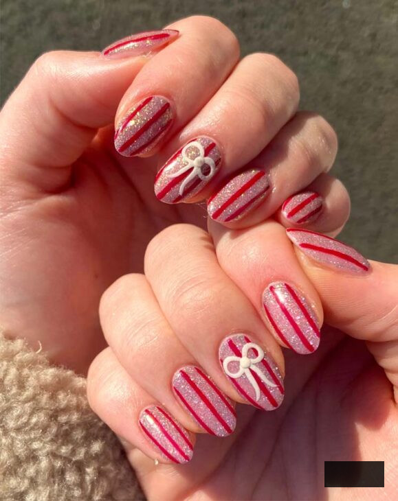 glittery pink and red stripe christmas almond nails with white bow design