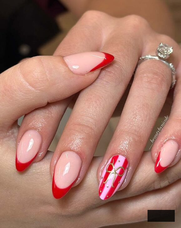 elongated aesthetic almond scarlet fuchsia Christmas nail art with hand-drawn gold bow on scarlet tips