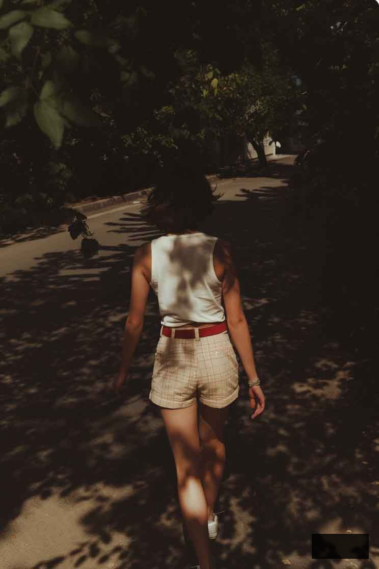 cute light academia summer outfit with mini cotton plaid shorts and white tank styled with belt and sneakers