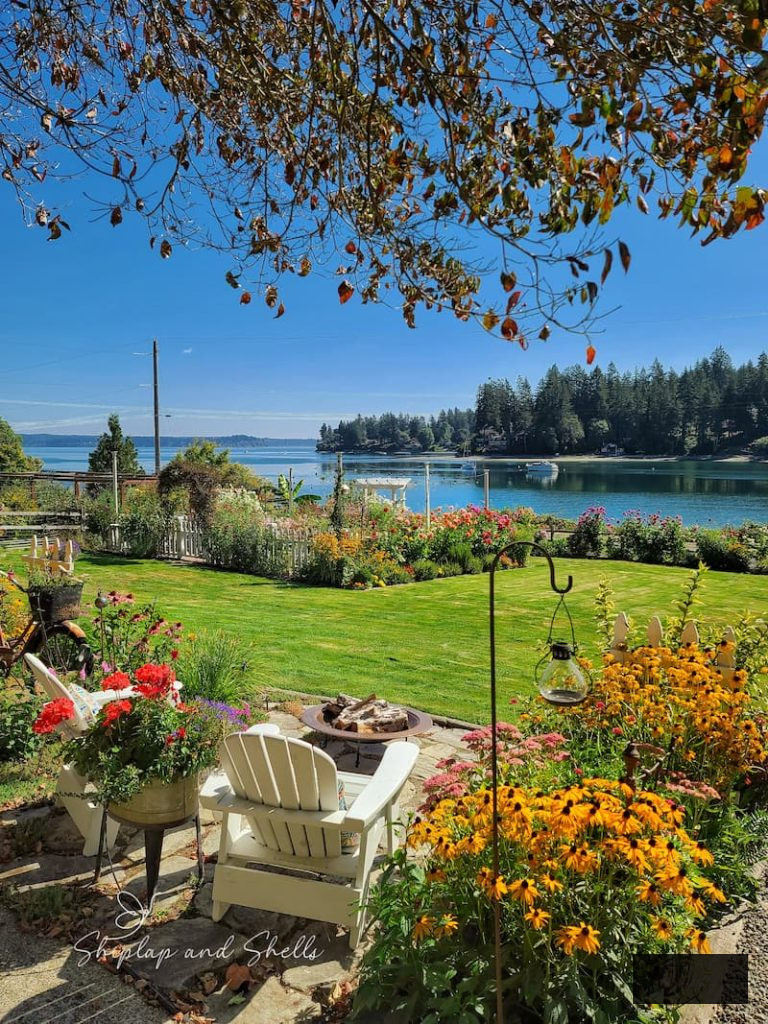 outdoor seating and firepit in the garden with a view of the bay in late summer