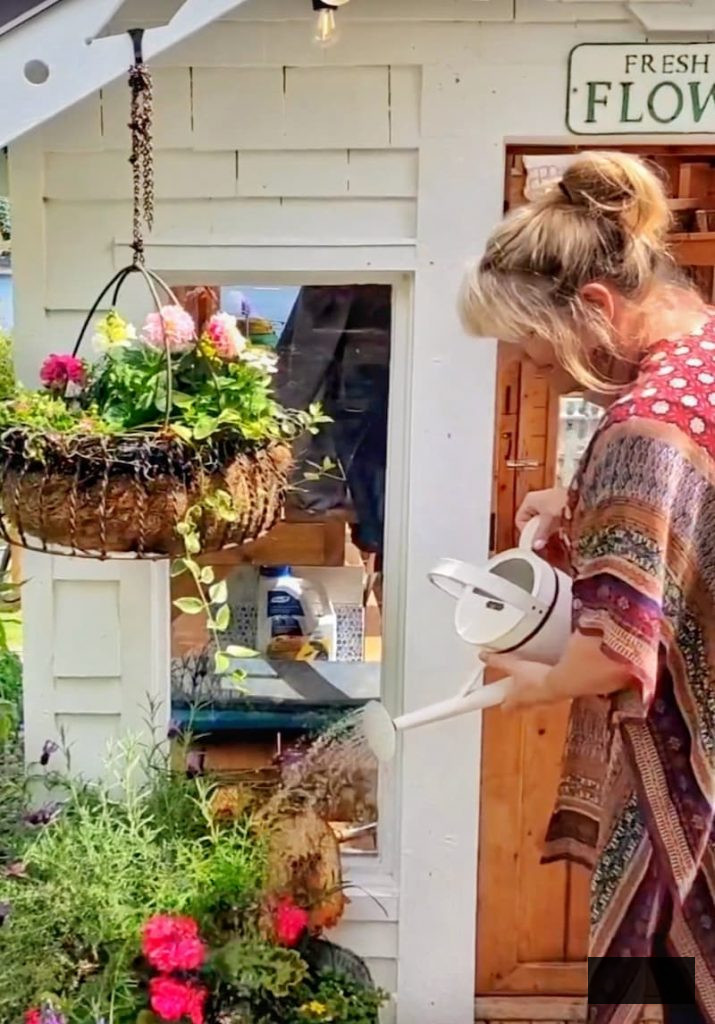 watering the plants in front of the greenhouse