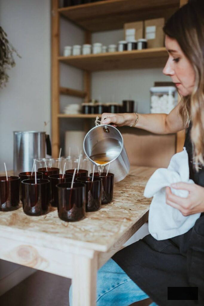 Individual pouring wax into candle molds during a crafting workshop