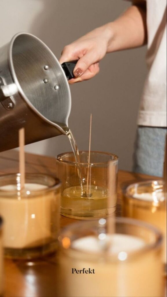 Person pouring wax into glass jars during a DIY candle making tutorial