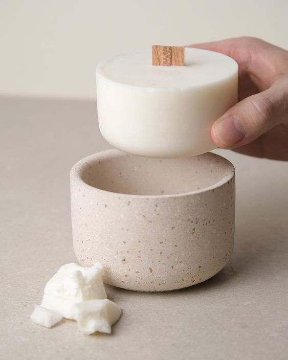 Hand placing a soy wax candle into a textured container for candle crafting