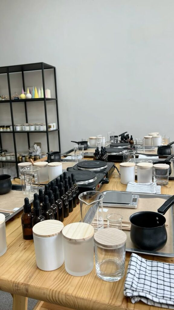 Candle making workshop setup with jars, beakers, droppers, and hot plates
