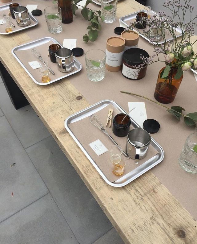 DIY candle making workspace with jars, trays, and tools on a wooden table