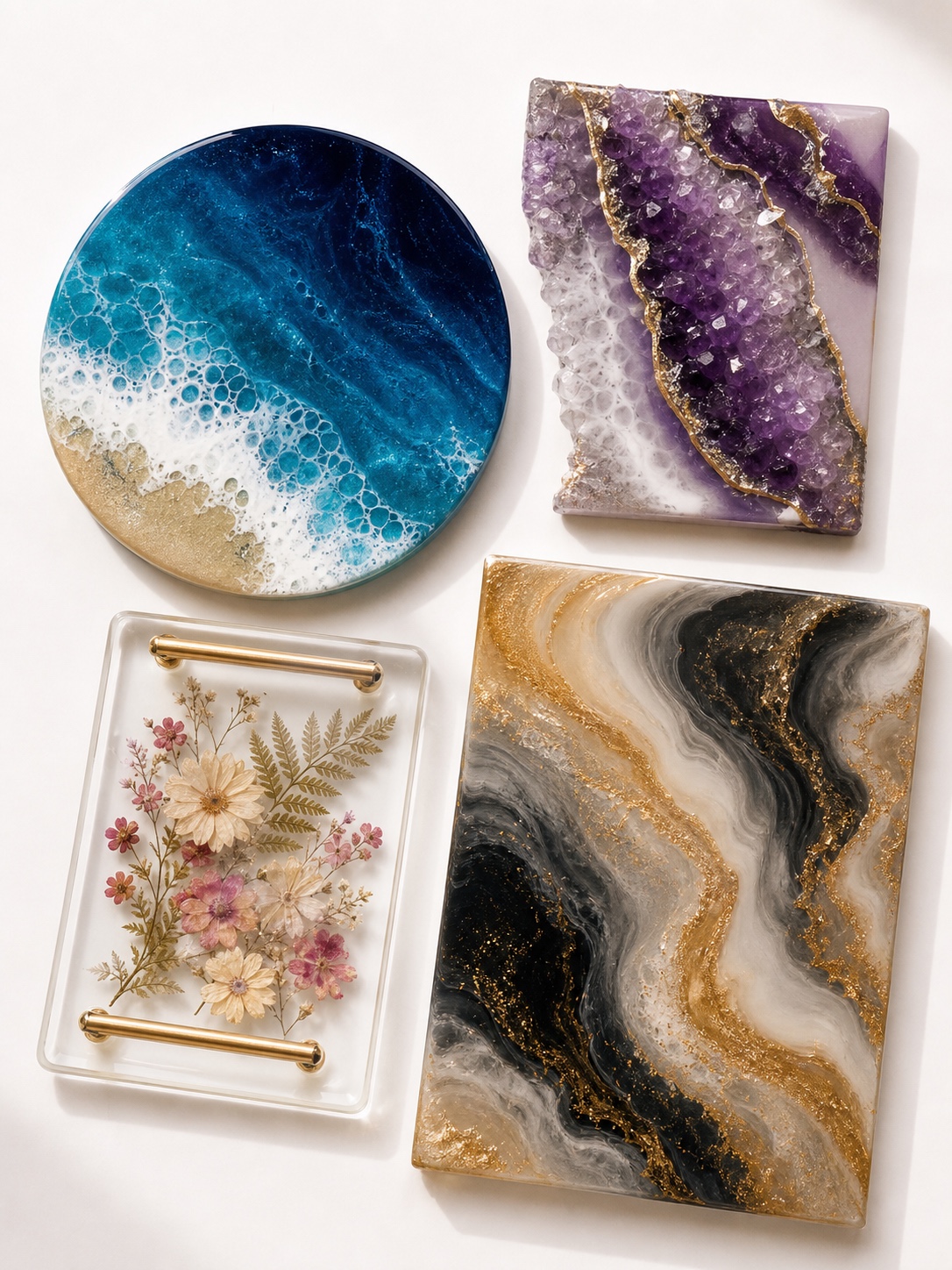 Resin art project concepts flat lay Circular blue ocean-themed resin tray with frothy white waves and sandy border, along with three rectangular geode and marble pieces in violet, gold, black, and white shades with metallic features; a transparent floral tray with gold handles is also shown. | Sky Rye Design Flat lay of completed resin art project concepts including an ocean coaster, geode panel, floral tray, and gold swirl pour.