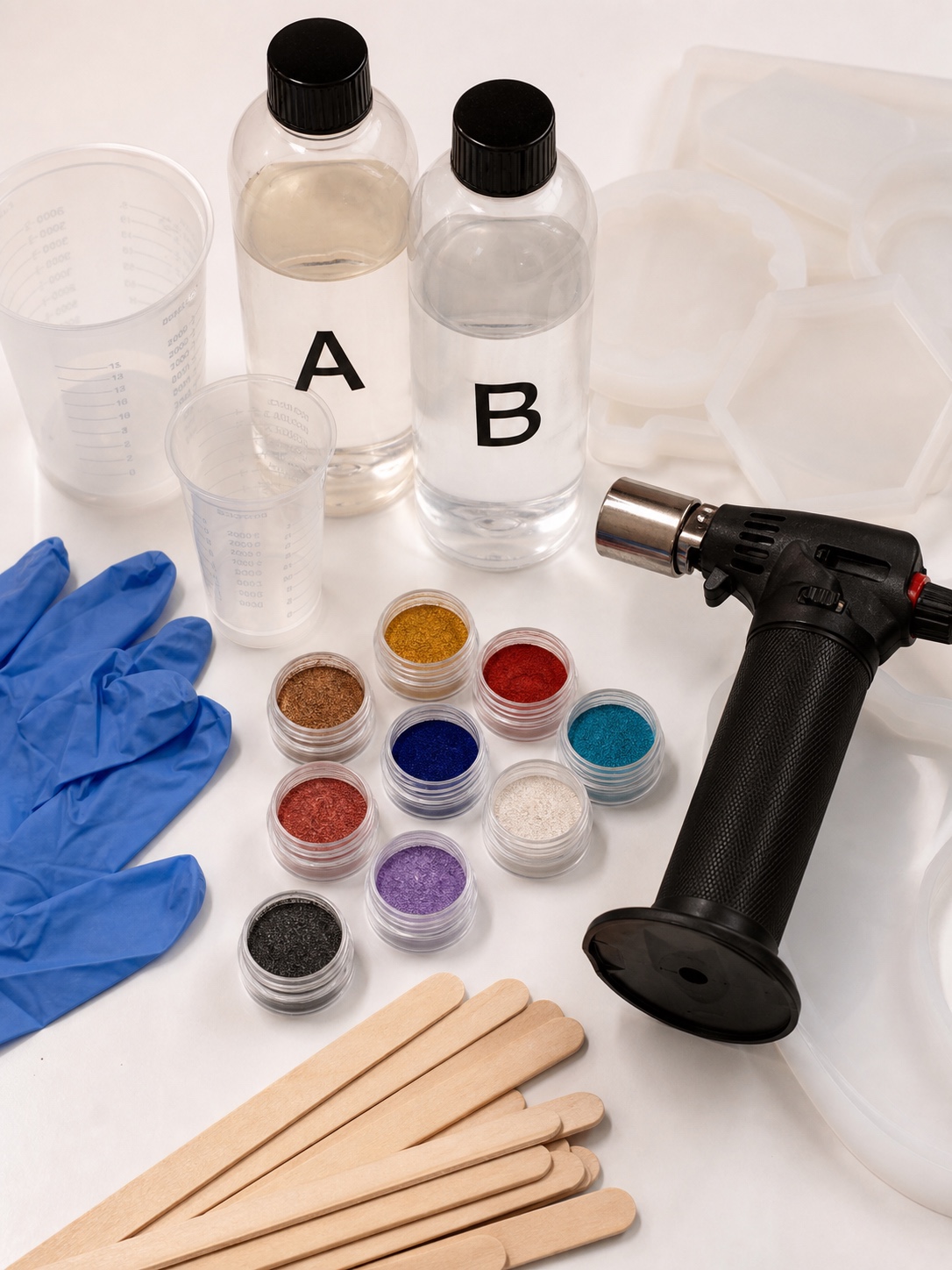 Resin art supplies flat lay Overhead arrangement of epoxy resin bottles, measuring cups, silicone molds, gloves, pigments and a torch. | Sky Rye Design Overhead arrangement of epoxy resin bottles, measuring cups, silicone molds, gloves, pigments and a torch.