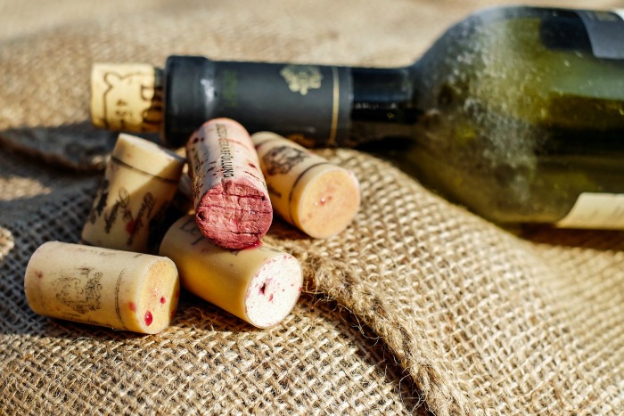 Garrafa de vinho e rolhas de vinho sobre juta.