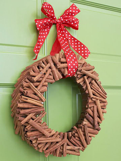 Guirlanda de Palitos de Canela do bhg.com em uma porta verde com um laço vermelho e branco.