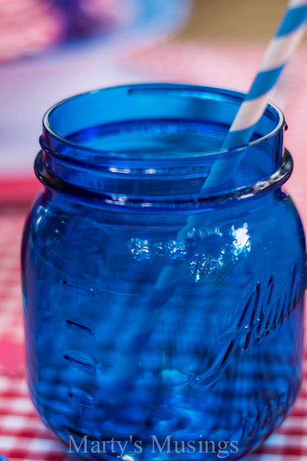Um copo com uma garrafa azul, com guardanapo e pote