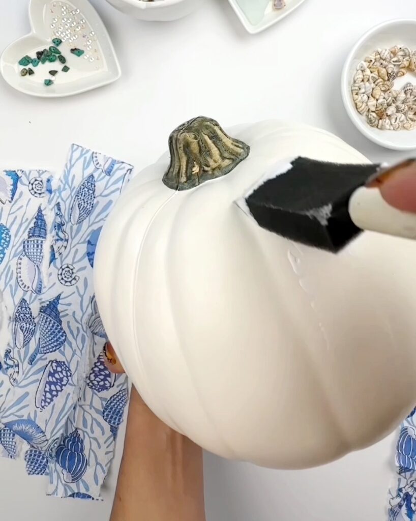adicionando mod podge à abóbora antes da decoupage