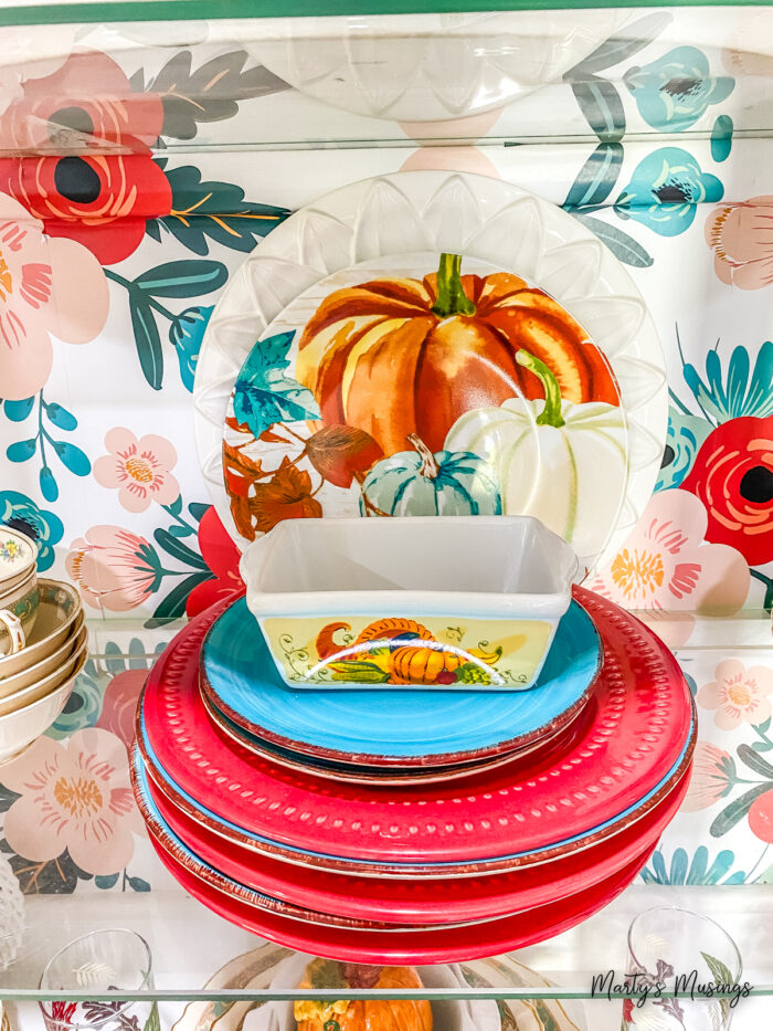 Aparador com papel de parede floral e decoração de outono dentro