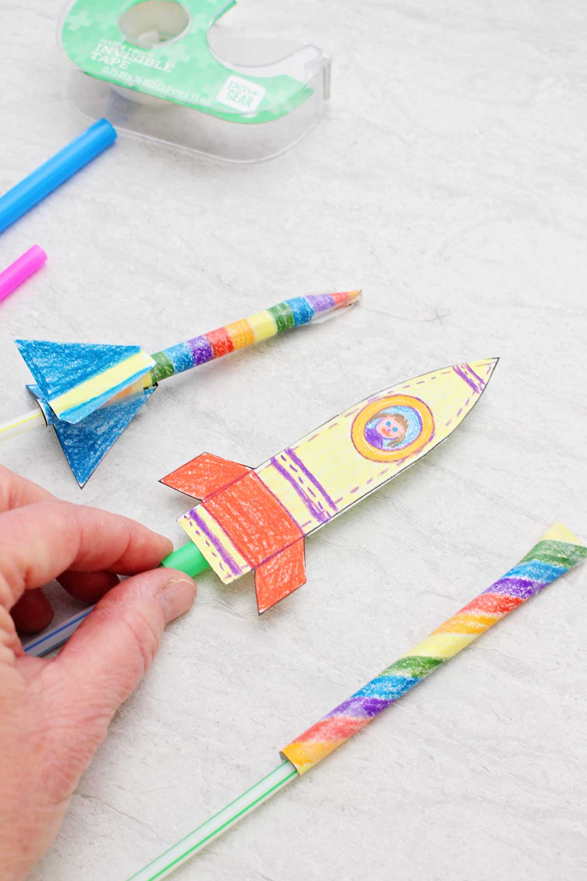 Três foguetes de canudo coloridamente pintados.