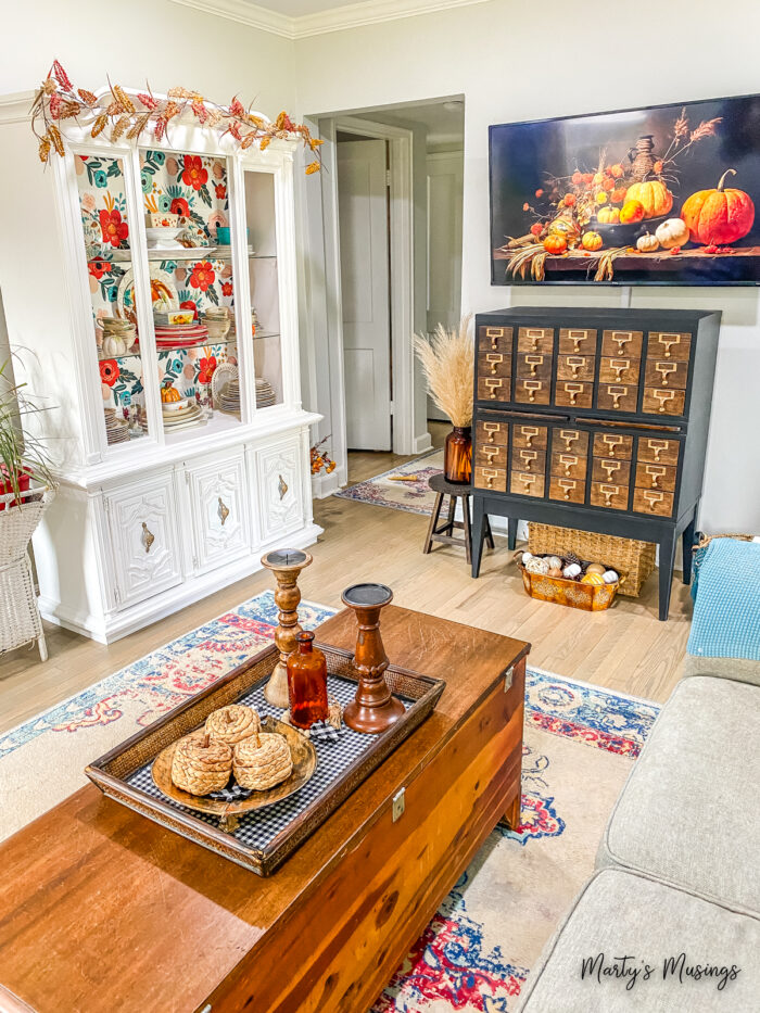 Sala de estar pequena com aparador branco e catálogo de cartões vintage decorados para o outono