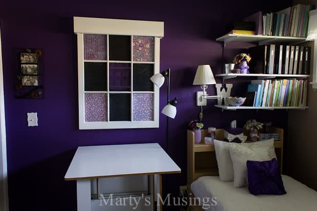 Um quarto com uma cama e uma mesa em um pequeno espaço
