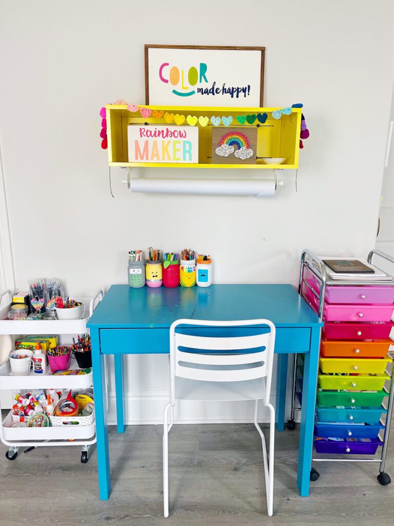Carrinhos de armazenamento com rodas ao lado de uma mesa pequena para criar um espaço de artesanato organizado