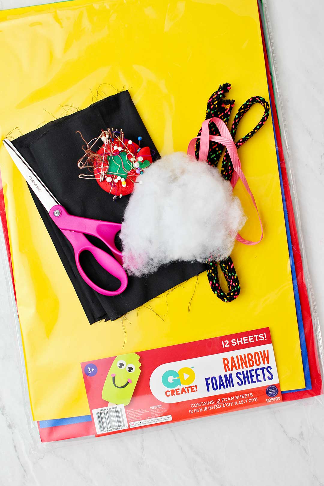 Um pacote de folhas de espuma coloridas e diversos materiais para fazer a fantasia de gato preto para o Halloween.