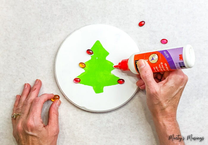 Adicionando pedras vermelhas à árvore de Natal estampada em verde