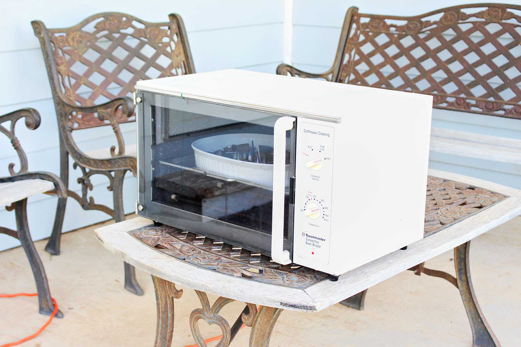 Um forno elétrico em cima de uma mesa ao ar livre em uma varanda.